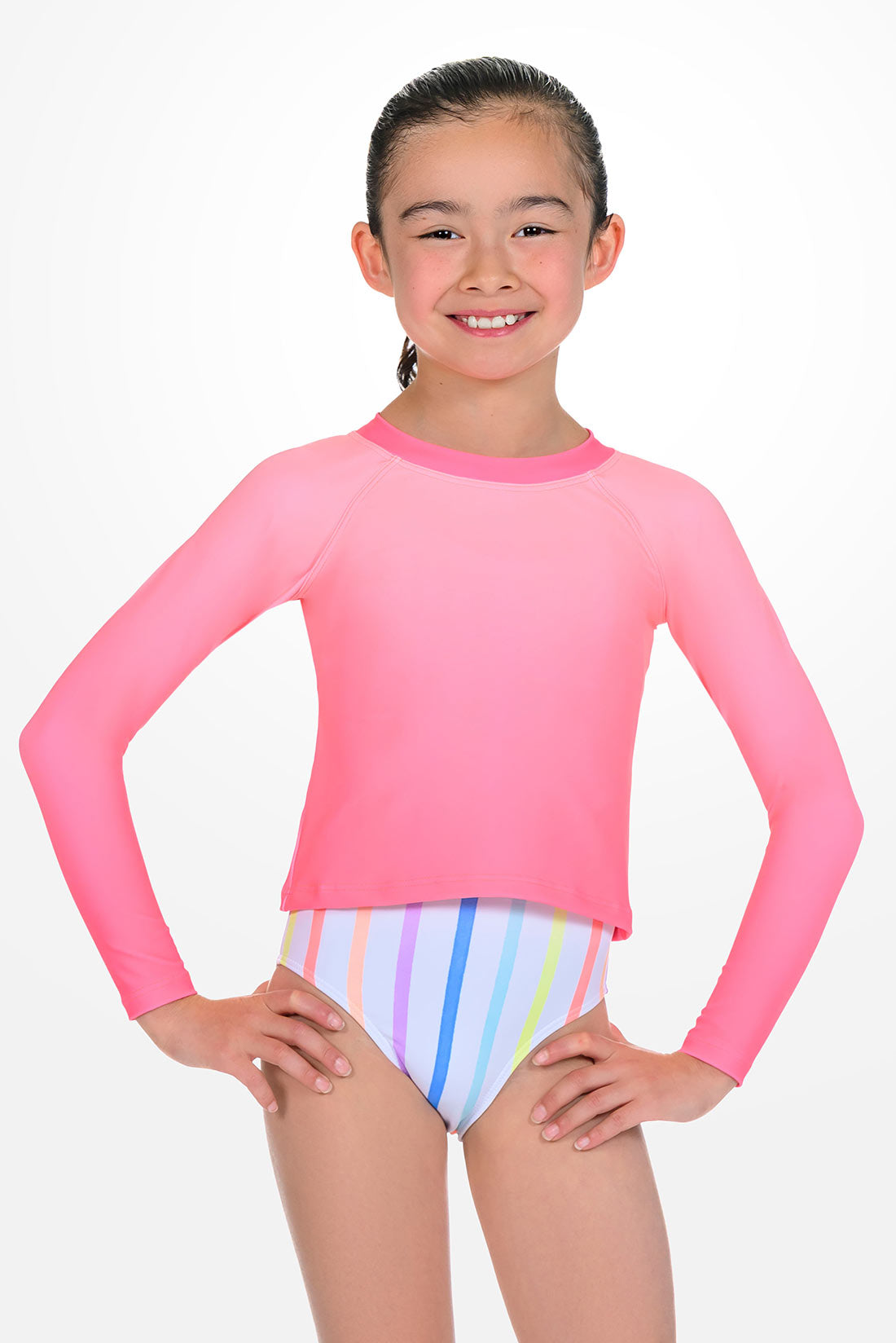 Girl wearing a pink long-sleeve rash guard top and multicolored striped swimsuit
