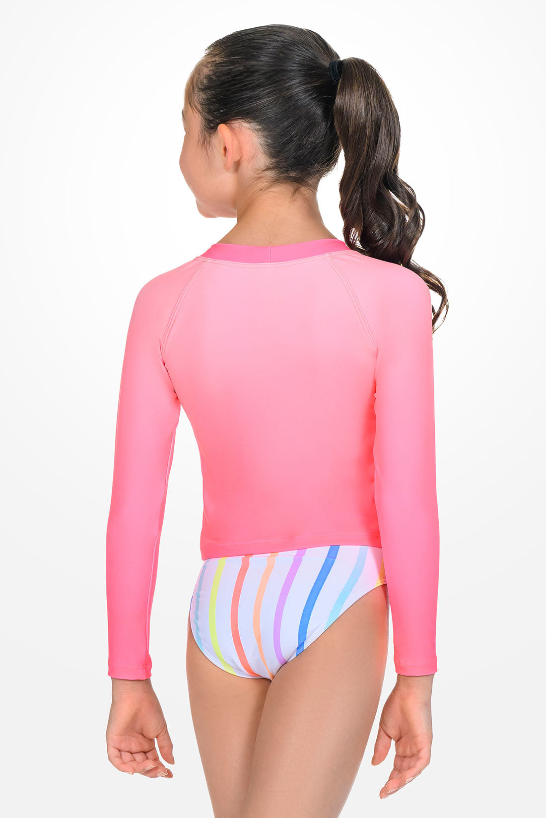 Girl wearing a pink long-sleeve rash guard and multicolored striped swimsuit
