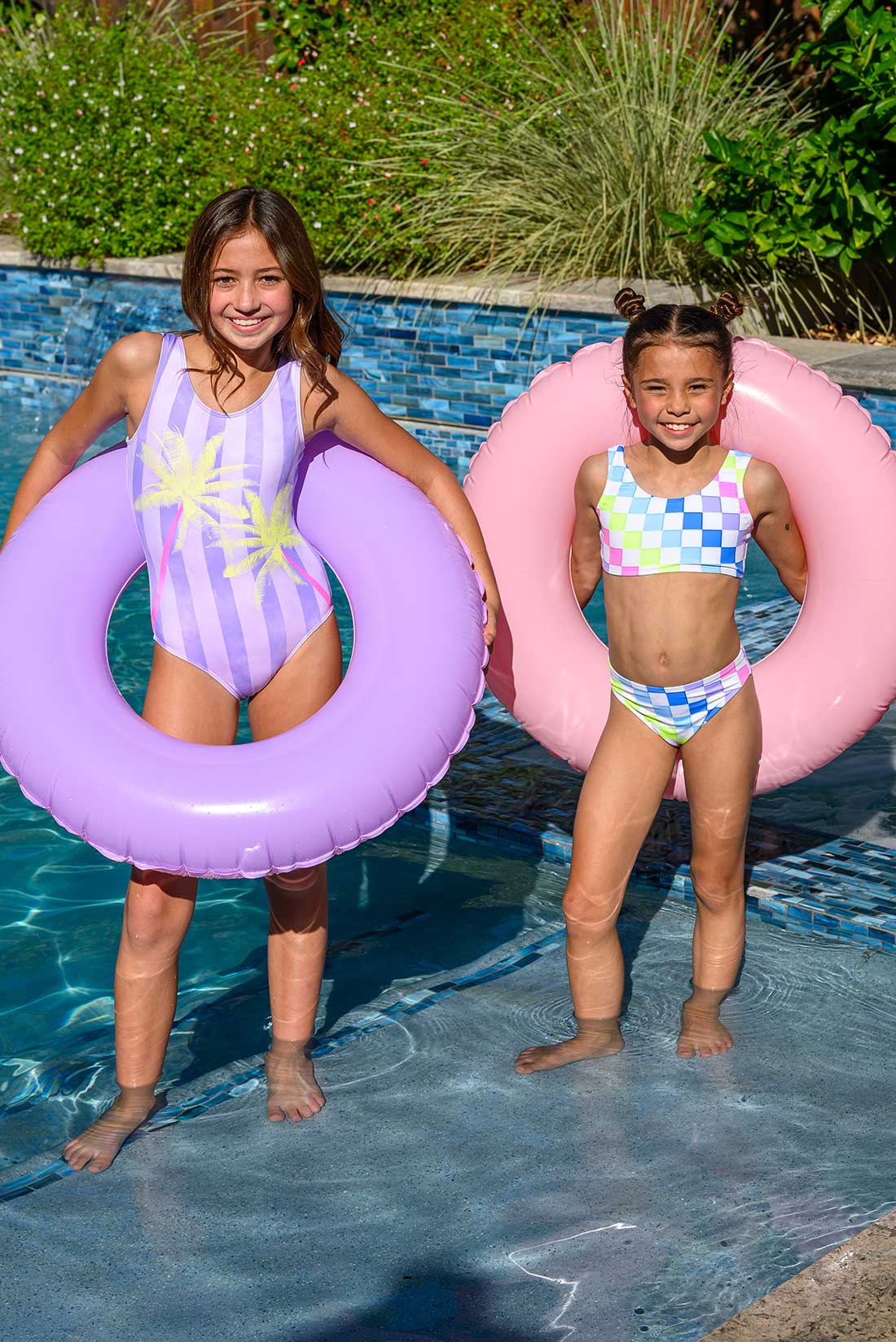Two girl gymnasts with inflatable floaties in a pool having fun