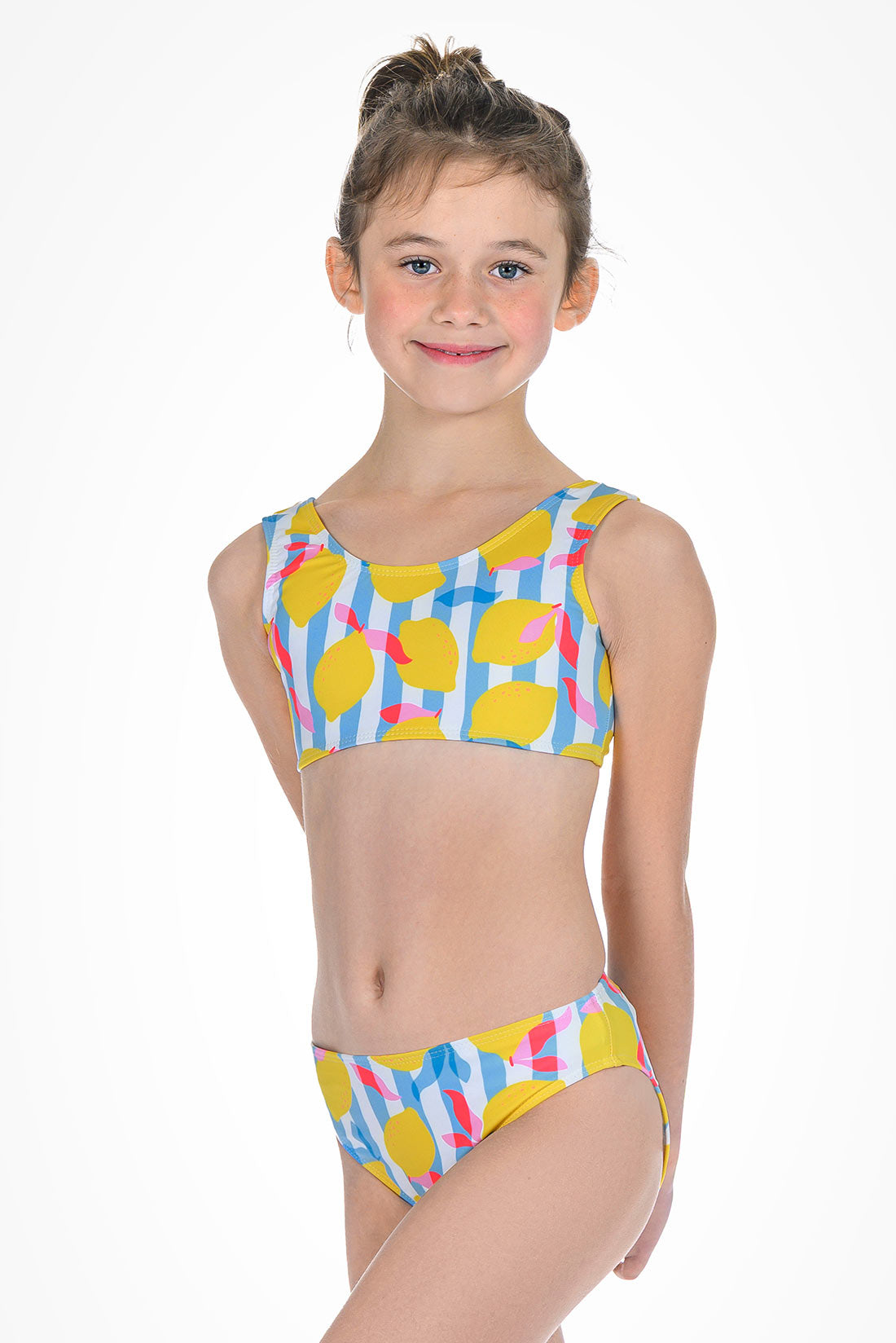 Young girl wearing a colorful bikini with a lemon pattern on a white background showing front view